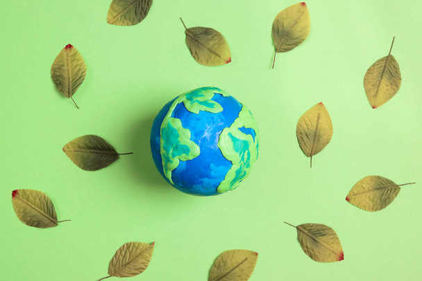 Globe surrounded by leaves on a green background. Earth Day, ecology and nature protect. - Foto, Imagem