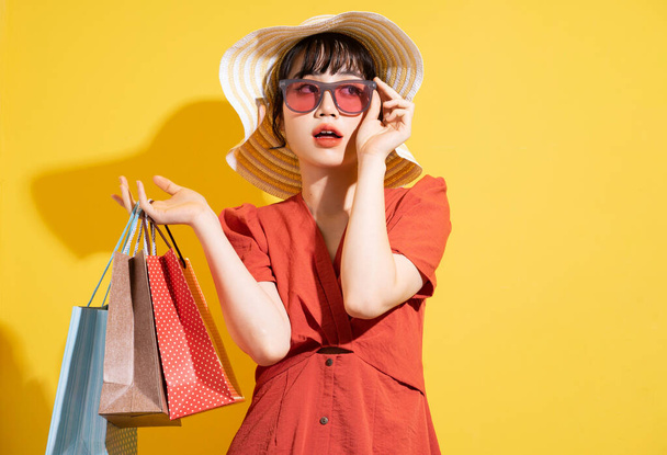 Νεαρή Ασιάτισσα επιχειρηματίας που κρατάει τσάντες για ψώνια και ποζάρει σε κίτρινο φόντο - Φωτογραφία, εικόνα