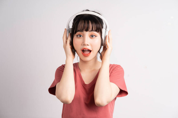 Młoda Azjatka używająca bezprzewodowych słuchawek do słuchania muzyki - Zdjęcie, obraz
