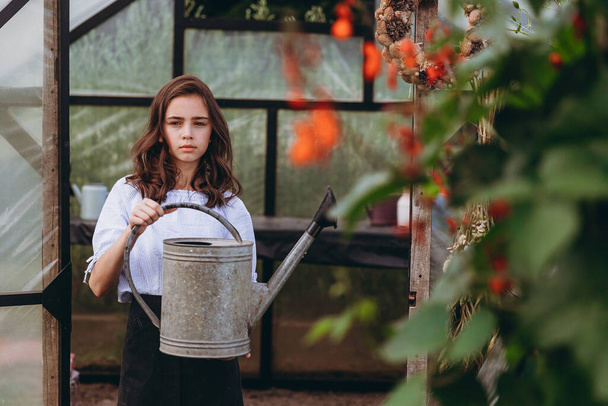 Cute 13-year-old child girl carrying basket of beautiful flower in the flower field with happiness - Foto, immagini