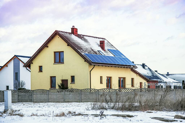 Kışın kırsal bir evin çatısındaki güneş fotovoltaik panelleri. - Fotoğraf, Görsel