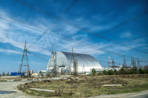 Pripyat stad, Kiev regio, Oekraïne - 13 april 2019: metalen hangar onderdak op de vierde noodcentrale van de kerncentrale van Tsjernobyl en een gedenkteken voor de slachtoffers van de Tsjernobyl ramp - Foto, afbeelding