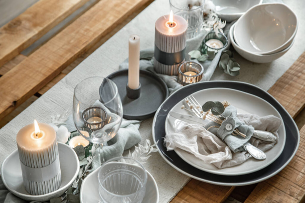 Close up detail of a festive table setting with a set of cutlery, a plate and candles in candlesticks. - 写真・画像