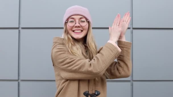 Γυναίκα με γυαλιά χειροκροτεί και γελάει στο γκρι φόντο - Πλάνα, βίντεο
