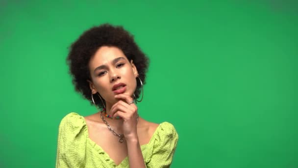 Focalizzato afro-americano donna guardando la fotocamera isolata sul verde  - Filmati, video