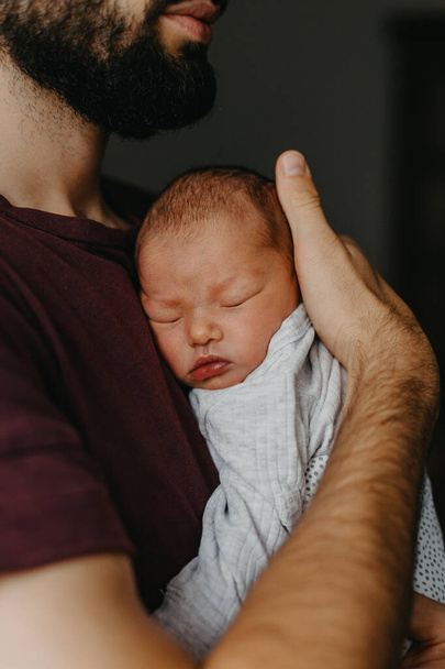 home photos of a newborn baby in the arms of father. Selective focus, noise effect - Фото, изображение