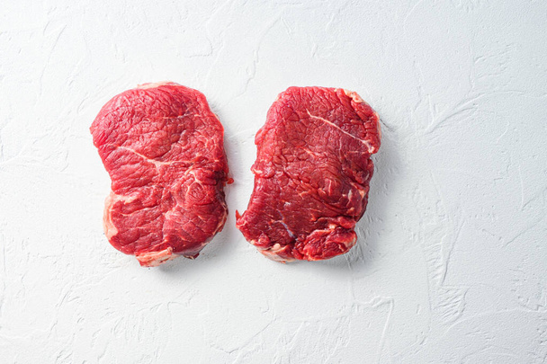 Μπριζόλα, βιολογικό ωμό κρέας μοσχαρίσιου κρέατος Λευκό ανάγλυφο φόντο. Κάτοψη με κενό για κείμενο - Φωτογραφία, εικόνα