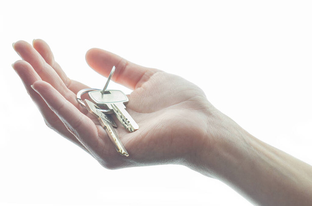 Woman hand holds a key isolated on a white background. - Zdjęcie, obraz