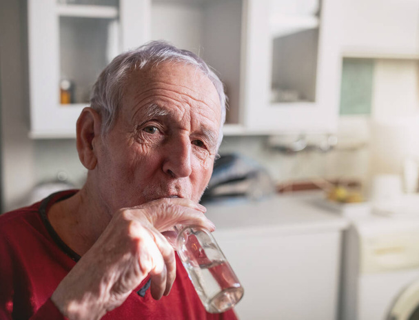 Старший мужчина пьет ракию, крепкий алкогольный напиток дома - Фото, изображение