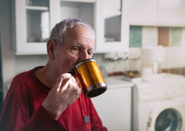 Vieil homme dans ses années 90 boire du thé de tasse dans la cuisine à la maison - Photo, image