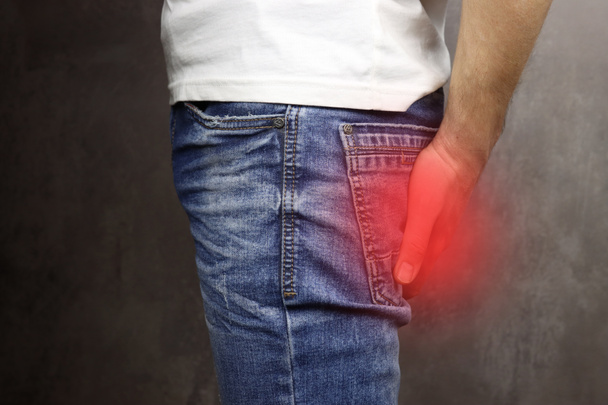 человек с геморроем держа свою задницу, красная зона боли - Фото, изображение