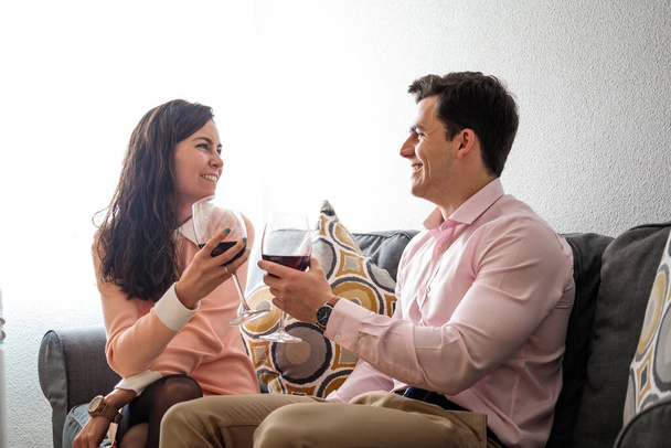 Young happy couple romantic date drink glass of red wine at home - Photo, Image