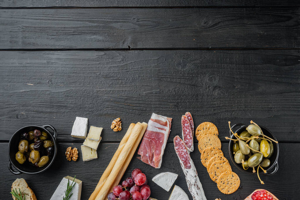 Włoskie przekąski, ser mięsny, zestaw ziół, na czarnym drewnianym stole, widok z góry z miejsca na tekst - Zdjęcie, obraz
