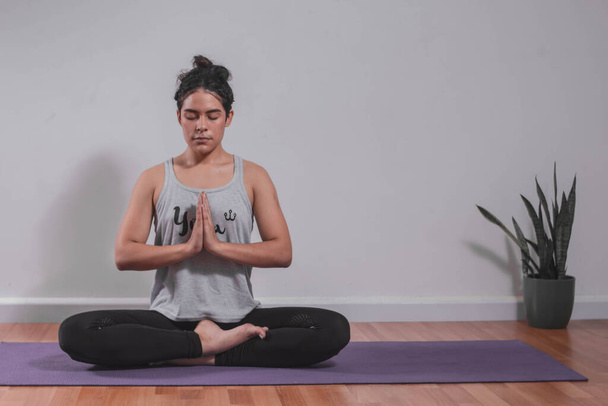 Fiatal nő meditál jóga szőnyegen a stúdióban - Fotó, kép