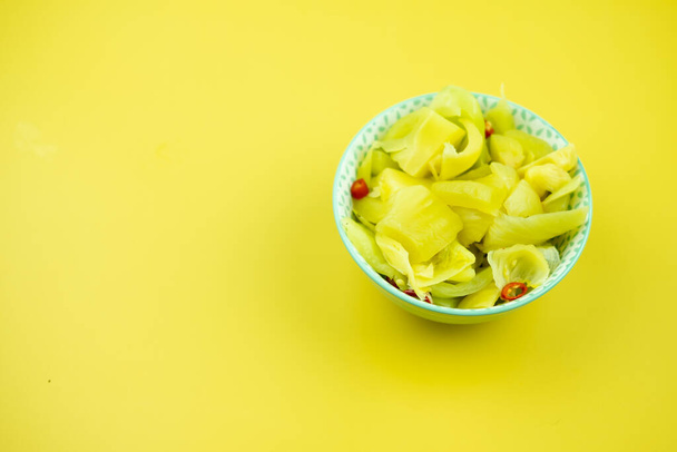 Würziger eingelegter Kohlsalat in Schüssel auf gelbem Hintergrund. Traditionelle würzige Beilage im Asia-Restaurant. - Foto, Bild