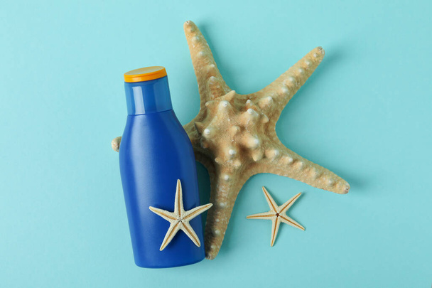 Blaue Flasche Sonnencreme und Seesterne auf blauem Hintergrund - Foto, Bild