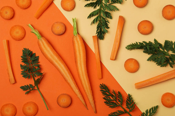 Slices and leaves of fresh carrot on two tone background - Photo, image