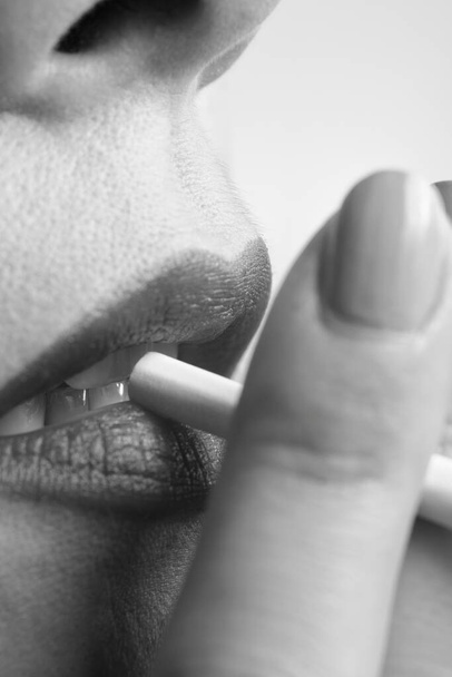 Primer plano de una mujer con labios sensuales fumando un cigarrillo en blanco y negro - Foto, imagen