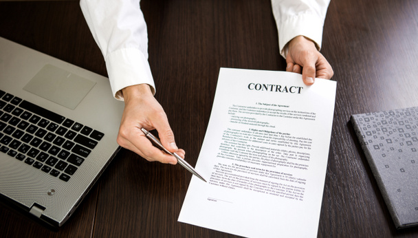 Biznesmen przekazujący kontrakt na podpis z długopisem w ręku. - Zdjęcie, obraz