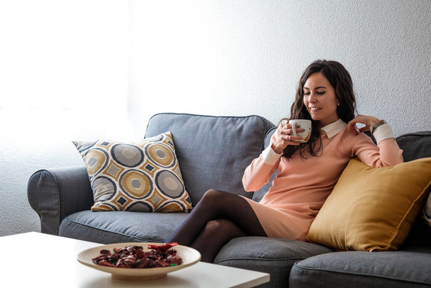Kaunis nuori nainen juo kahvia ja rentoutuu huoneessa. Muotokuva latinalaisamerikkalainen - Valokuva, kuva