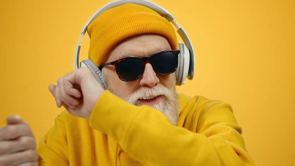 Vidám idős férfi gesztikulál a modern stúdióban. Stílusos srác szórakozás beltérben. - Fotó, kép