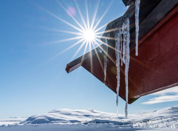 El primer plano de un largo carámbano colgando de un techo en un día frío de inviernos. Foto de alta calidad - Foto, Imagen