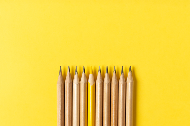 One yellow pencil standing out from the series of gray pencils. - Foto, imagen