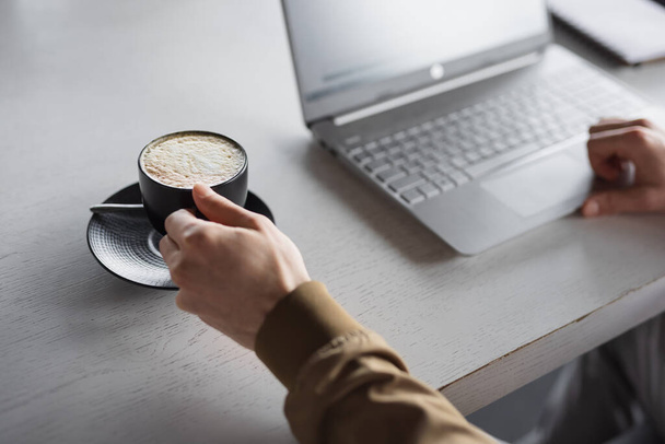 Closeup male hands working on laptop keyboard take a cup of latte - Fotoğraf, Görsel