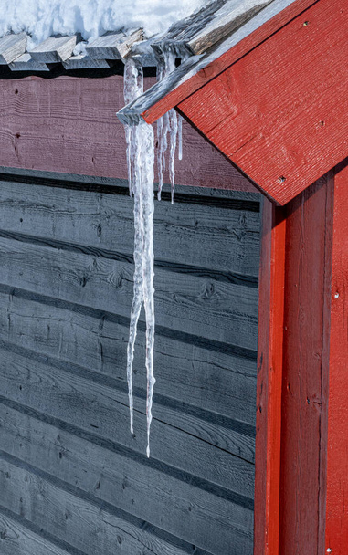 Soğuk bir kış gününde çatıdan sarkan uzun bir buz sarkıtı.. - Fotoğraf, Görsel