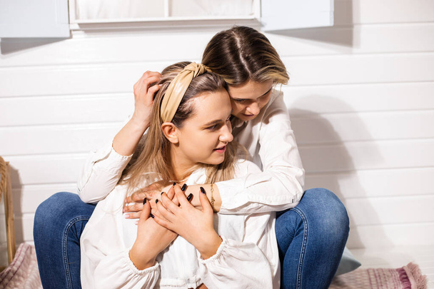 Couple of young beautiful women lesbians gently communicate in their node or in hotel. Concept of homosexual relationships in the family - Photo, Image
