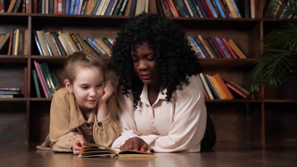 Afro-américaine belle-mère et fille blonde lire conte de fées - Séquence, vidéo