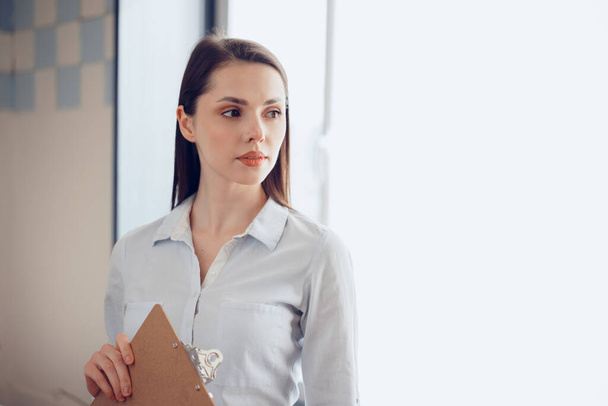 Portrait of a young attractive businesswoman holding clipboard in office - Photo, image