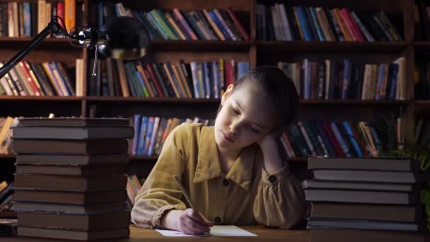 Müdes Mädchen schreibt Hausaufgaben nach Büchern auf Blatt Papier - Filmmaterial, Video