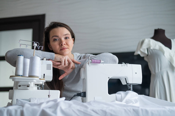 Young caucasian woman sews at home - Фото, изображение