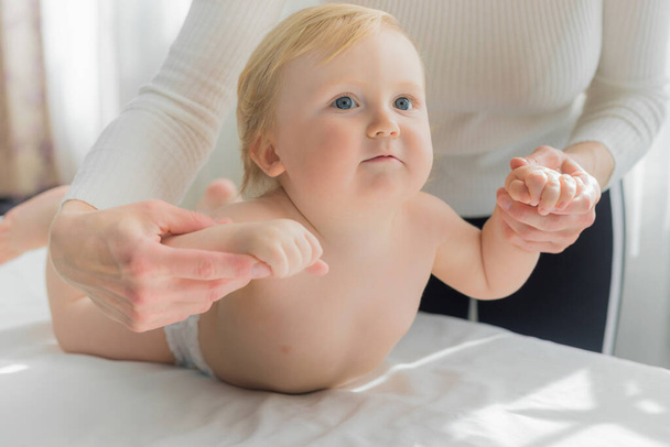 Mom does hand exercises to the baby. Close-up. - Foto, Bild