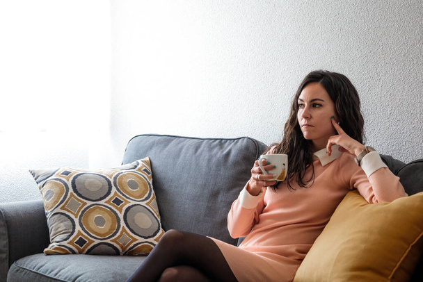 Beautiful young woman drinking coffee and relaxing in the room. Portrait of hispanic - Zdjęcie, obraz