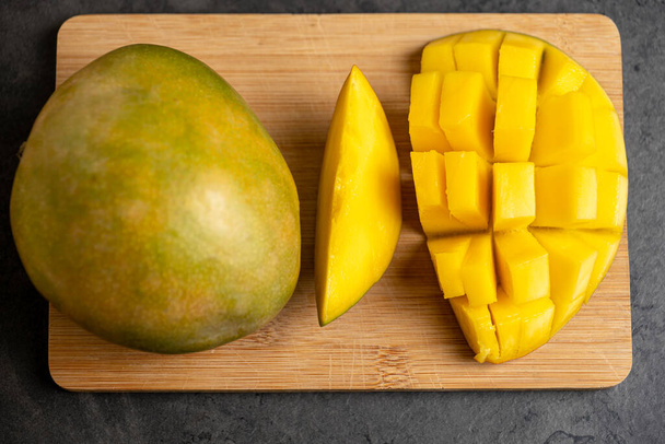 ripe mango cut into cubes on a dark gray background - Photo, Image