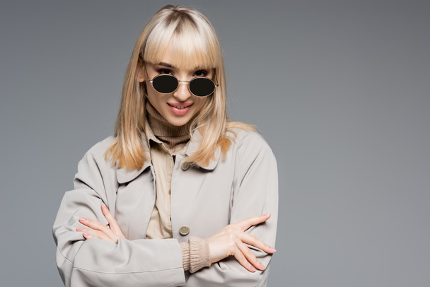 blonde and cheerful woman in sunglasses posing isolated on grey - Фото, зображення