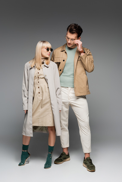 full length of stylish young couple posing on grey - Φωτογραφία, εικόνα