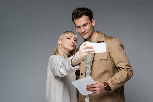 stylish models posing while taking selfie isolated on grey - Фото, зображення