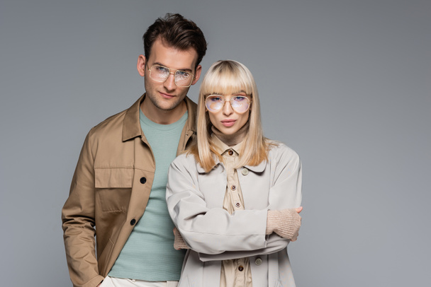 stylish couple in glasses posing and looking at camera isolated on grey - Fotografie, Obrázek