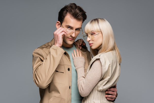 stylish couple in glasses hugging while posing isolated on grey - Фото, изображение