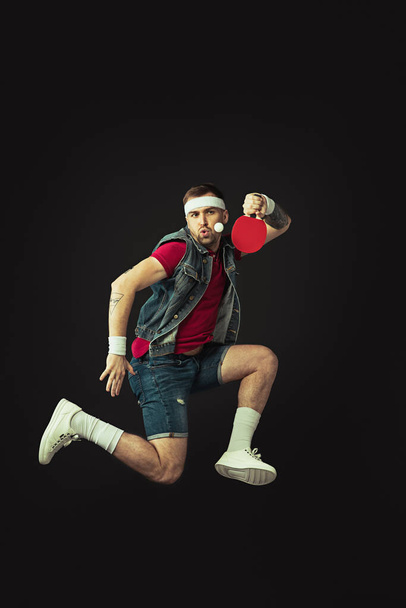 Fiatal kaukázusi vicces férfi játszik ping pong elszigetelt fekete háttér. - Fotó, kép