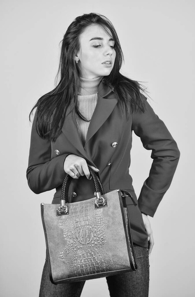 Fits perfect. Beauty brunette. Fashionable woman in jacket. Fashion autumn winter. female trendy beauty. handbag and accessories. Trendy girl holding small leather bag in hand. Stylish accessories - 写真・画像
