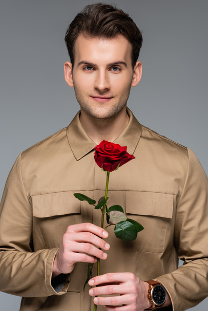 smiling man holding red rose isolated on grey - Valokuva, kuva