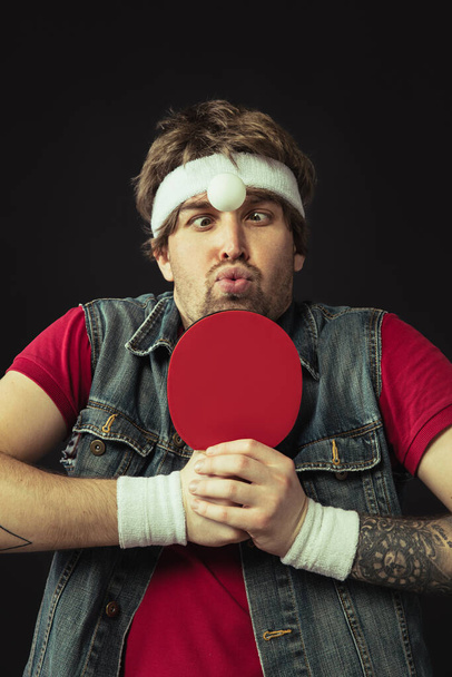 Young Caucasian funny man playing ping pong isolated on black background. - Photo, Image