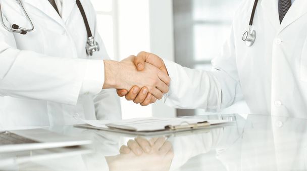 Two doctors are shaking hands as agreement about patients treatment, close-up. Medical help, medicine concept - Fotó, kép