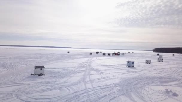 Πετώντας πίσω με ένα drone, κινείται μακριά από το χωριό ψάρεμα στον πάγο με ένα όμορφο ηλιοβασίλεμα στο παρασκήνιο - Πλάνα, βίντεο