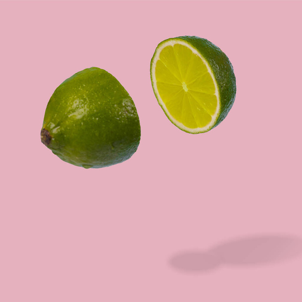 Minimal idea with fresh lime sliced on pastel pink background. Minimal fruit concept.Vitamins, healthy diet concept. Sliced lime floating in the air. Creative concept with flying fruits. - Foto, afbeelding