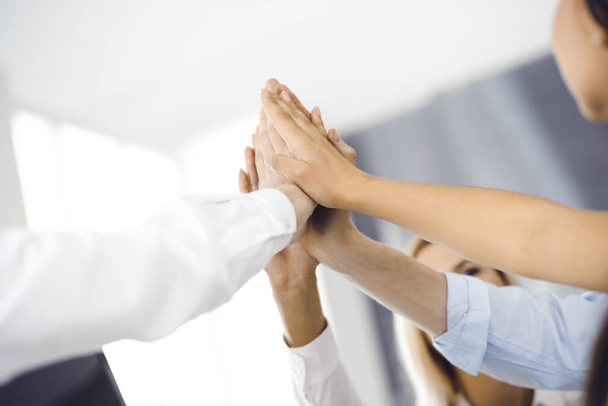Group of business people joining hands or giving five to each other after meeting or negotiation in modern office. Colleagues showing teamwork, cooperation and partnership in corporate occupation - Photo, image